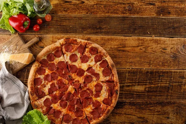 木製のテーブルの上のペパロニピザ。食材を使った静物。トップビュー。スペースのコピー. — ストック写真