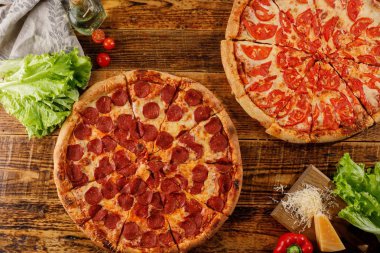 Pizza Pepperoni ve Margarita tahta bir masada. Malzemelerle natürmort.