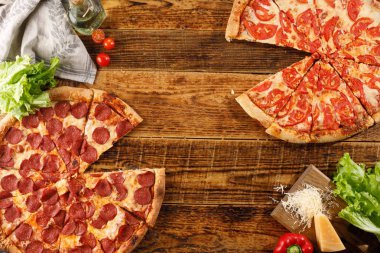 Pizza Pepperoni ve Margarita tahta bir masada. Malzemelerle natürmort. Üstte görüntü.