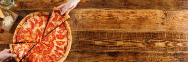 Pizza Margarita tahta bir masada. Elleri ve malzemeleri ile natürmort. Üstte görüntü.