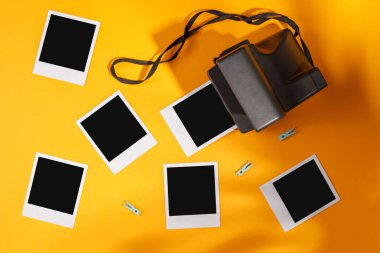 Sarı arkaplanda fotoğraf çerçeveleri ve kamera var. Anıların korunması kavramı. Düz yatıyordu.