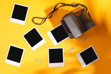 Sarı arkaplanda fotoğraf çerçeveleri ve kamera var. Anıların korunması kavramı. Düz yatıyordu.