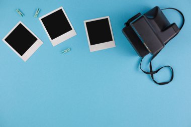 Mavi arka planda anlık fotoğraf çerçeveleri ve kamera. Anıların korunması kavramı. Düz yatıyordu.