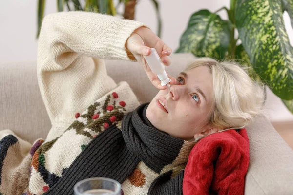 스웨터입은 여자 애가 소파에 누워 아프대. 감기와 독감이었습니다. 환자는 감기에 걸려 아프다는 느낌 이들어 콧등에 주사를 놓았다. 건강하지 못한 여자. — 스톡 사진