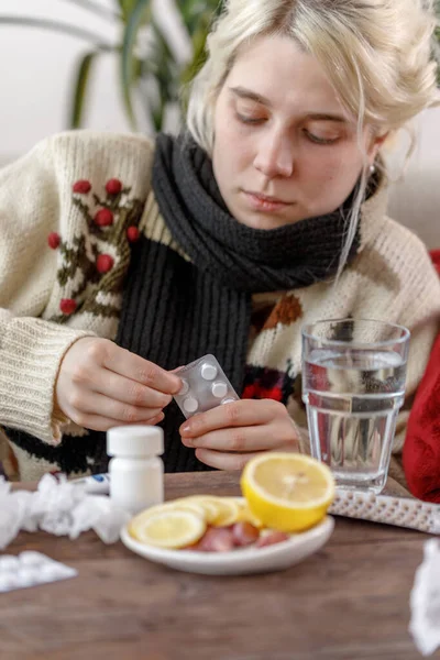 A lány a pulóverben rosszul van a kanapén fekve. Megfázás és influenza. A beteg megfázott, rosszul lett, és gyógyszereket használ a kezelésre. Egészségtelen lány.. — Stock Fotó