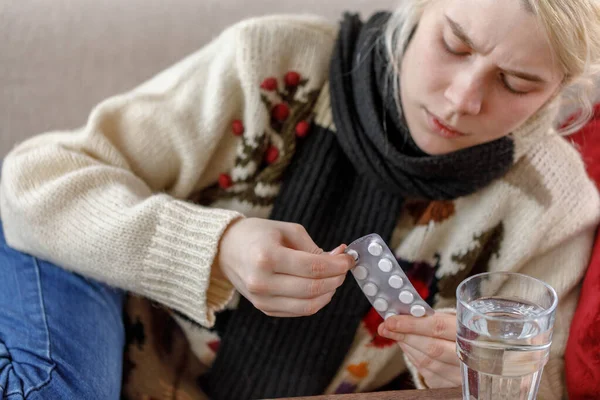 Дівчинка в светрі хвора лежить на дивані. Застуда і грип. Пацієнт застудився, захворів і використовує таблетки для лікування. Нездорові дівчата . — стокове фото