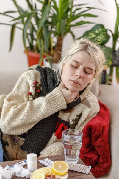 A lány a pulóverben rosszul van a kanapén fekve. Megfázás és influenza. A beteg megfázott, rosszul lett és torokgyulladása volt. Egészségtelen lány torokfájással. — Stock Fotó