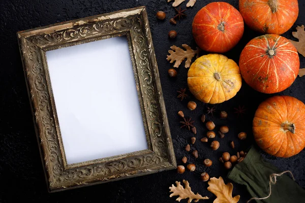 Autumn frame made of pumpkins, tree leaves, hazelnuts on black background. Autumn, fall, thanksgiving concept. Flat lay, copy space.