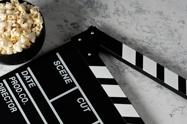 Clapper board with popcorn. Movie concept. Clapperboard on a textural background. Close-up.