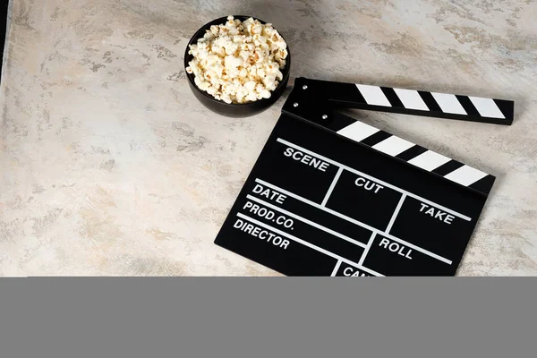 Clapper board with popcorn. Movie concept. Clapperboard on a textural background. Close-up.