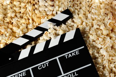Patlamış mısırlı el çırpma tahtası. Film konsepti. Arka planda patlamış mısır krakeri var. Yakın plan..