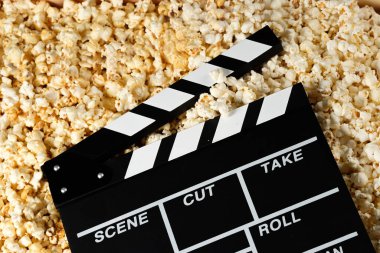 Patlamış mısırlı el çırpma tahtası. Film konsepti. Arka planda patlamış mısır krakeri var. Yakın plan..