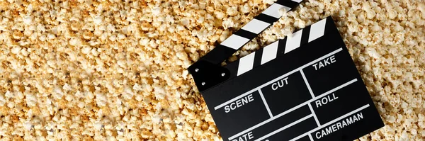 Clapper board with popcorn. Movie concept. Popcorn cracker on the background. Close-up.