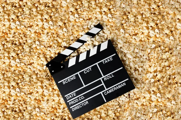 Clapper board with popcorn. Movie concept. Popcorn cracker on the background. Close-up.