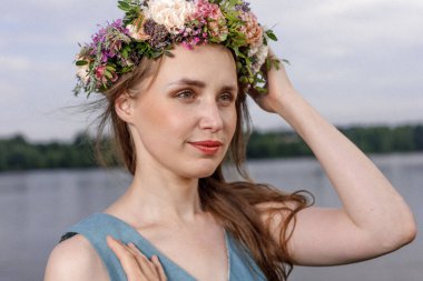 Kafasında çiçek çelengi olan Slav güzeli doğanın kucağında. Antik putperest kökenli kutlama konsepti. Yaz gündönümü günü. Yaz ortası.