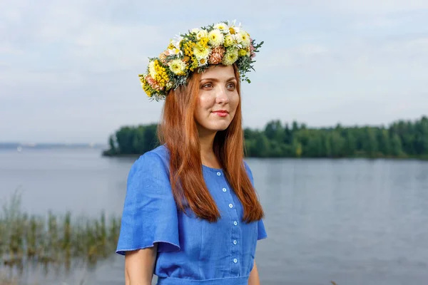 Slavic beauty with a flower wreath on her head in the lap of nature. Ancient pagan origin celebration concept. Summer solstice day. Mid summer.