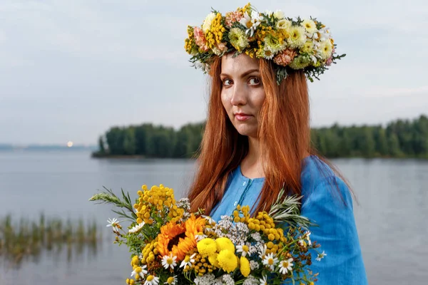 Kafasında çiçek çelengi ve bir buket kır çiçeğiyle Slav güzelliği. Antik putperest kökenli kutlama konsepti. Yaz gündönümü günü. Yaz ortası.
