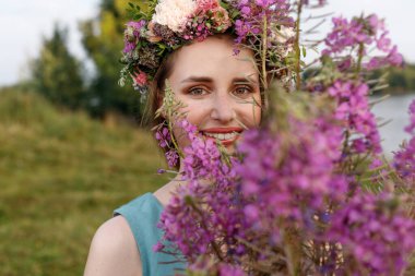 Kafasında çiçek çelengi ve bir buket kır çiçeğiyle Slav güzelliği. Antik putperest kökenli kutlama konsepti. Yaz gündönümü günü. Yaz ortası.
