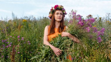 Kafasında çiçek çelengi ve bir buket kır çiçeğiyle Slav güzelliği. Antik putperest kökenli kutlama konsepti. Yaz gündönümü günü. Yaz ortası.