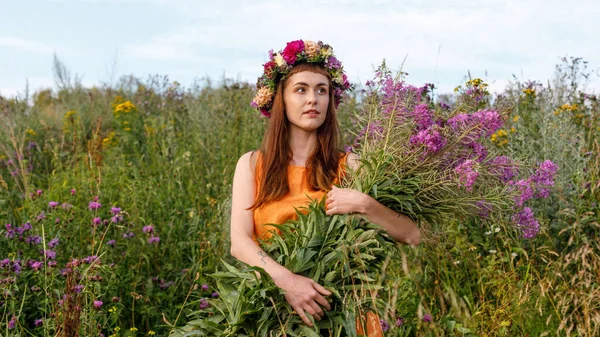 Kafasında çiçek çelengi ve bir buket kır çiçeğiyle Slav güzelliği. Antik putperest kökenli kutlama konsepti. Yaz gündönümü günü. Yaz ortası.