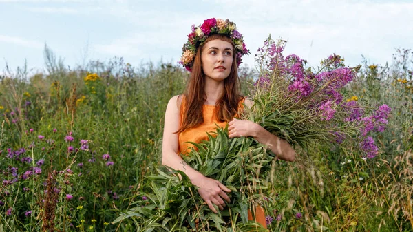 Kafasında çiçek çelengi ve bir buket kır çiçeğiyle Slav güzelliği. Antik putperest kökenli kutlama konsepti. Yaz gündönümü günü. Yaz ortası.