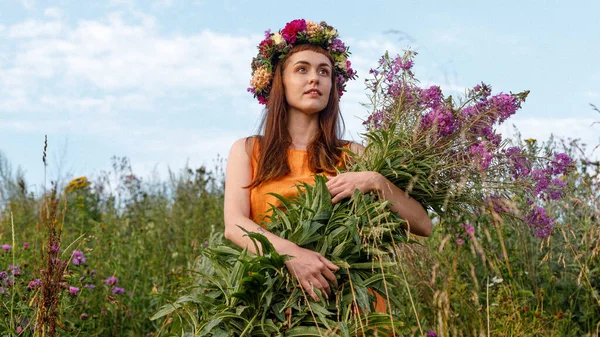 Kafasında çiçek çelengi ve bir buket kır çiçeğiyle Slav güzelliği. Antik putperest kökenli kutlama konsepti. Yaz gündönümü günü. Yaz ortası.