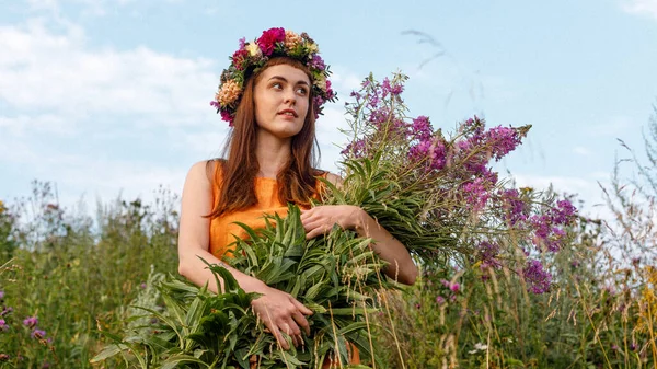 Kafasında çiçek çelengi ve bir buket kır çiçeğiyle Slav güzelliği. Antik putperest kökenli kutlama konsepti. Yaz gündönümü günü. Yaz ortası.
