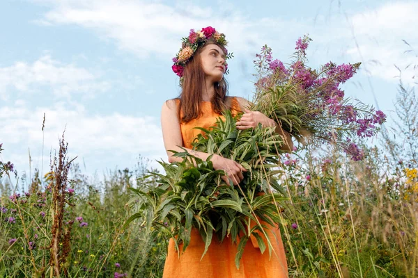 Kafasında çiçek çelengi ve bir buket kır çiçeğiyle Slav güzelliği. Antik putperest kökenli kutlama konsepti. Yaz gündönümü günü. Yaz ortası.