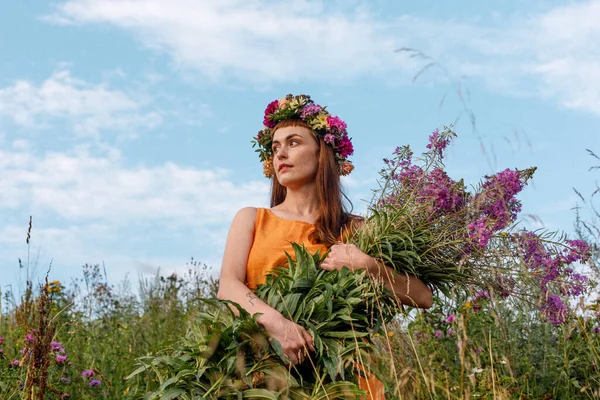 Kafasında çiçek çelengi ve bir buket kır çiçeğiyle Slav güzelliği. Antik putperest kökenli kutlama konsepti. Yaz gündönümü günü. Yaz ortası.