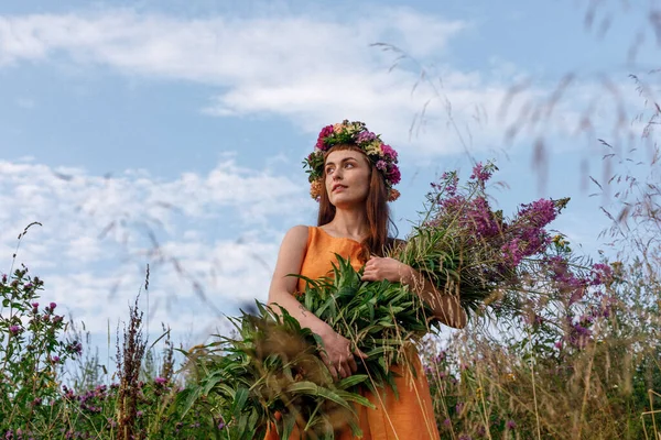 Kafasında çiçek çelengi ve bir buket kır çiçeğiyle Slav güzelliği. Antik putperest kökenli kutlama konsepti. Yaz gündönümü günü. Yaz ortası.
