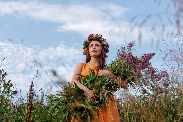 Kafasında çiçek çelengi ve bir buket kır çiçeğiyle Slav güzelliği. Antik putperest kökenli kutlama konsepti. Yaz gündönümü günü. Yaz ortası.