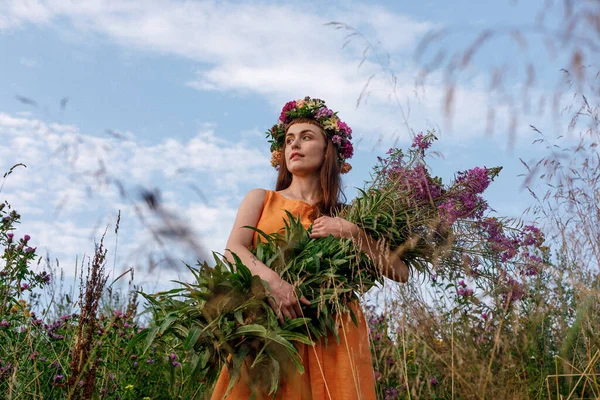 Kafasında çiçek çelengi ve bir buket kır çiçeğiyle Slav güzelliği. Antik putperest kökenli kutlama konsepti. Yaz gündönümü günü. Yaz ortası.