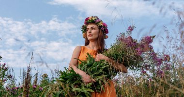 Kafasında çiçek çelengi ve bir buket kır çiçeğiyle Slav güzelliği. Antik putperest kökenli kutlama konsepti. Yaz gündönümü günü. Yaz ortası.