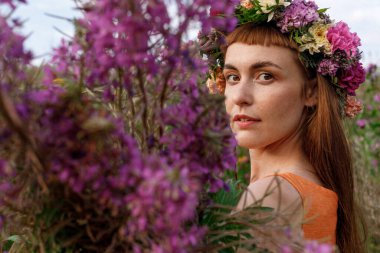 Kafasında çiçek çelengi ve bir buket kır çiçeğiyle Slav güzelliği. Antik putperest kökenli kutlama konsepti. Yaz gündönümü günü. Yaz ortası.
