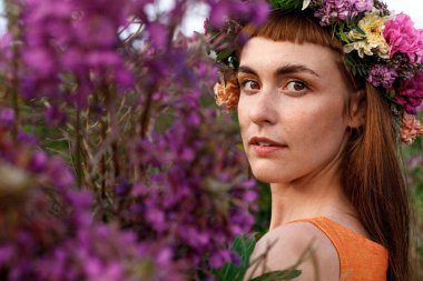 Kafasında çiçek çelengi ve bir buket kır çiçeğiyle Slav güzelliği. Antik putperest kökenli kutlama konsepti. Yaz gündönümü günü. Yaz ortası.