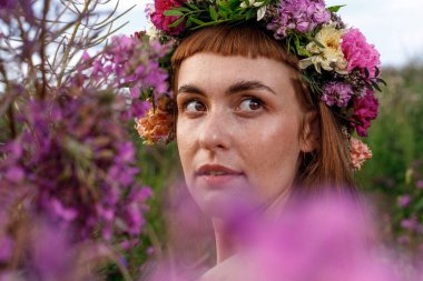 Kafasında çiçek çelengi ve bir buket kır çiçeğiyle Slav güzelliği. Antik putperest kökenli kutlama konsepti. Yaz gündönümü günü. Yaz ortası.