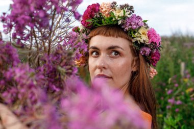 Kafasında çiçek çelengi ve bir buket kır çiçeğiyle Slav güzelliği. Antik putperest kökenli kutlama konsepti. Yaz gündönümü günü. Yaz ortası.