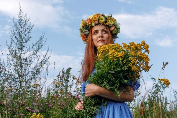 Kafasında çiçek çelengi ve bir buket kır çiçeğiyle Slav güzelliği. Antik putperest kökenli kutlama konsepti. Yaz gündönümü günü. Yaz ortası.