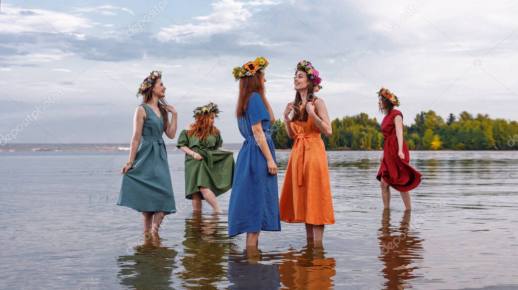 Lovely girls in flower wreaths in nature. Ancient pagan origin celebration concept. Summer solstice day. Mid summer.
