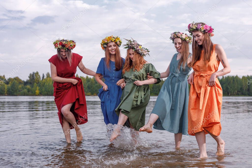 Lovely girls in flower wreaths in nature. Ancient pagan origin celebration concept. Summer solstice day. Mid summer.