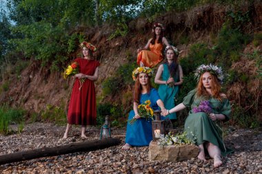 Doğada çiçek çelenkleri içinde güzel kızlar. Antik putperest kökenli kutlama konsepti. Yaz gündönümü günü. Yaz ortası.