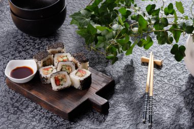 Sebzeli rulo ve susamlı balık ezmesi. Siyah arkaplanda servis edilen suşi rulosu. Lezzetli yemek..