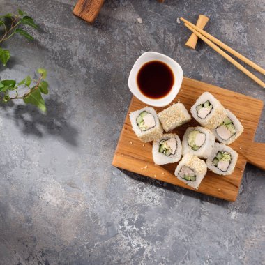 İçinde taze salatalık, tavuk ve salatadan yapılmış gri bir arka plan. Lezzetli yemek. Tahta bir tahtanın üzerinde bir parça rulo ile güzel, sakin bir hayat. Durgun hayat.