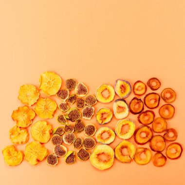 Turuncu arka planda kurutulmuş hurma, şeftali, erik ve incir dilimleri. Kurutulmuş meyve. Çevre. en üstteki görünüm.