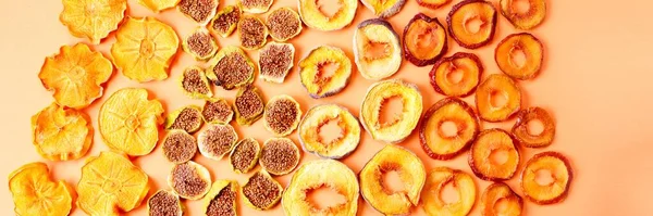 slices of dried persimmon, peach, plum and figs on a orange background. dried fruits. eco. top view.