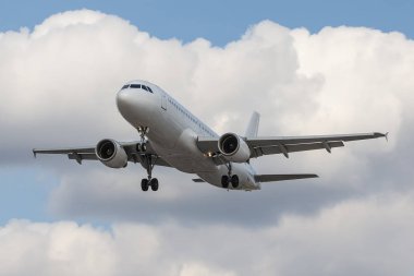 Adı yolcu uçağı bulutlu gökyüzü karşı havaalanına yaklaşırken, beyaz.