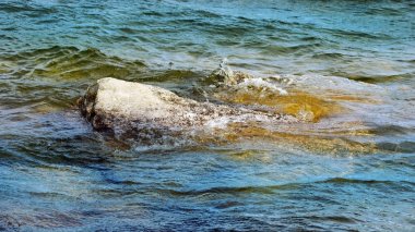 Büyük kayalara çarpan mavi ve yeşil güzel göl suları