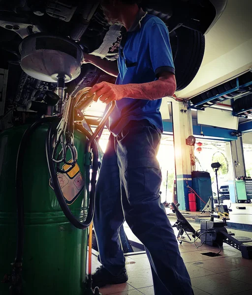 車のサービス 自動車修理のリフト車の下で働くプロフェッショナルな自動車メカニック男 — ストック写真