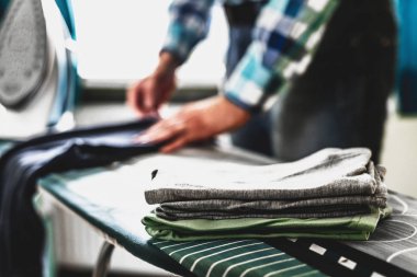 Adam evde elbise Ütü. Baba eve görevleri gerçekleştirir, çocuğun giysileri Irons. Bir adam bir kadının evde rolü. Adam Ütü forması ile mavi demir buharlı ütü masası.