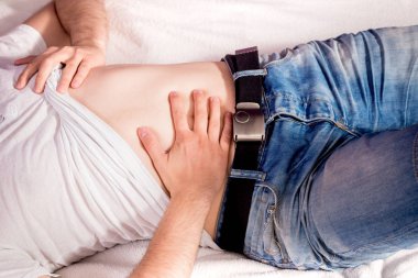 Mide ağrısı, karın ağrısı. Adam onun mide tutarak yatakta yatıyor. Tıbbi kavramı. Hazımsızlık, apandisit yaşamalı. Mide gribi.